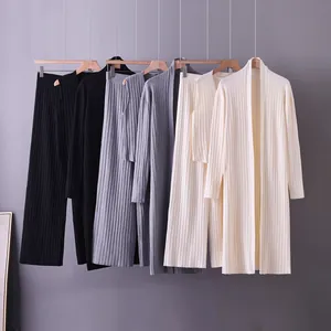 Three-piece women's ribbed knit sets in black, gray, and cream hanging on a clothes rack.