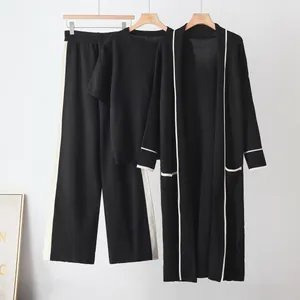 Detail of women's black 3-piece knit set with white contrast trim and long cardigan.