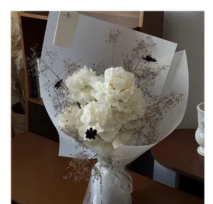 Elegant detail of frosted translucent floral wrapping paper on a white peony flower bouquet.