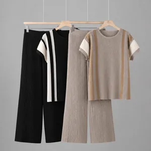 Detailansicht von zwei plissierten Stricksets mit farbigen Streifen an Holzkleiderbügeln.