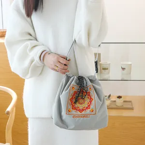 Sac à cordon de style japonais gris avec broderie mandala orange et poignée supérieure.