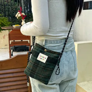 Detailed macro view of a green plaid woolen crossbody bag with a stylish woven strap.