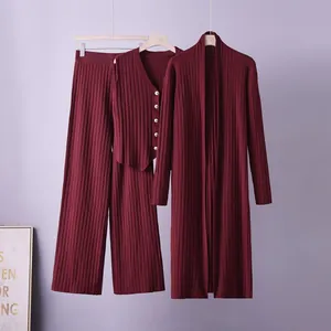 Close-up of elegant burgundy ribbed knit three-piece set including vest and cardigan