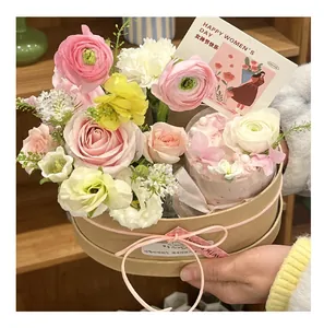 Close-up view of forest style oval kraft gift box containing fresh flowers and cakes