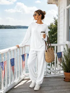 Close-up of white cable knit two-piece lounge set worn by a model on a lakeside balcony.