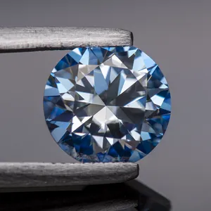 Close-up macro view of an ice blue round-cut moissanite gemstone held by metal tweezers