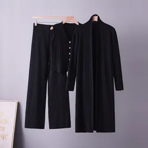 Detail shot of a black three-piece knitted cardigan set hanging on wooden hangers