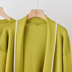 Detailed view showing the texture and contrast trim of a lime green knit robe on a hanger