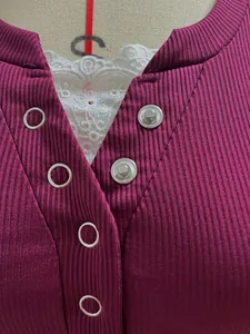 Close-up detail of women's ribbed knit top with lace trim and metal snap buttons