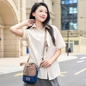 Mannequin asiatique portant un sac à bandoulière bicolore compact pour randonnée en plein air.