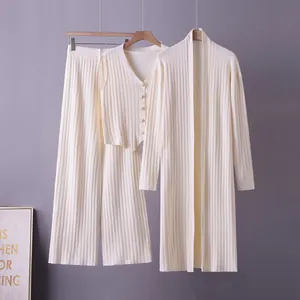 Detail view of a cream three-piece ribbed knit set featuring a cardigan, vest, and pants
