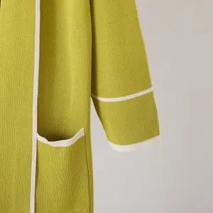 Close-up detail of soft green knitted robe featuring white contrast trim and fine texture