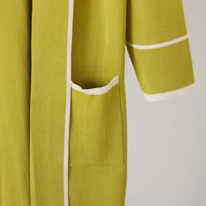 Macro view of green knitted robe featuring elegant white contrast trim and large pocket detail.