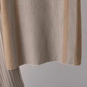 Detaillierte Nahaufnahme des plissierten Strickstoffs mit beigen und grauen Streifen.