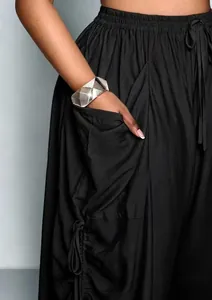 Dettaglio dei pantaloni a gamba larga a vita alta con coulisse e tasche laterali.