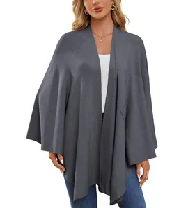 Vue détaillée d'un élégant poncho châle en tricot gris pour femme porté sur un haut blanc.