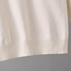 Primer plano del detalle de un jersey de punto blanco con textura de dobladillo acanalado