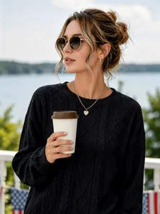 Detailed view of a woman wearing a stylish black cable knit crewneck sweater outdoors.