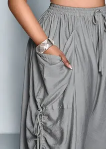 Dettaglio dei pantaloni larghi in lino grigio a vita alta con tasca e coulisse