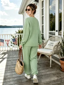 Back view of stylish light green cable knit sweater and jogger set at a lake house
