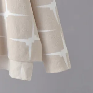 Close-up macro view of beige knitted fabric featuring white star jacquard pattern detail.