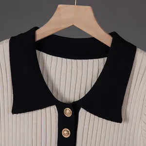 Macro close-up of contrast black polo collar and gold buttons on cream knit dress