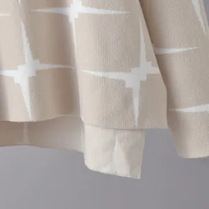 Close-up detail of jacquard knit fabric with star pattern on elegant beige sweater.