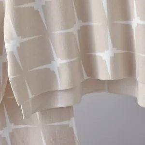 Close-up of beige and white jacquard star pattern on knitted fabric texture