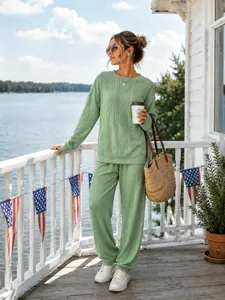 Close-up detail of a women's green cable-knit sweater and pants set in an outdoor setting.