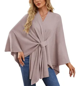 Vue détaillée d'un élégant poncho en maille mauve avec un design de nœud torsadé à l'avant.