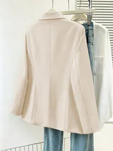 Detailed back view of a stylish beige slim-fit long-sleeved blazer hanging on a metal rack.