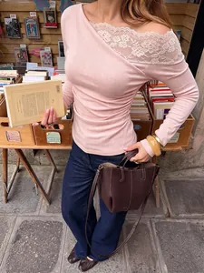 Detailed view of elegant French lace patchwork on a pink off-shoulder long-sleeve top.