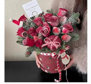 Close-up of a festive red Christmas flower bucket with roses and pine branches.