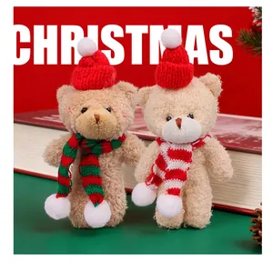 Close-up of two plush Christmas teddy bears with red hats and striped scarves