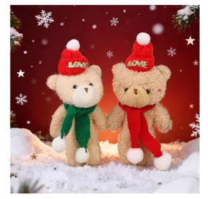 Adorable pair of beige Christmas teddy bear plush dolls standing in a snowy holiday scene.