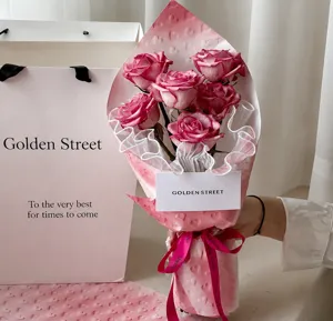 Close-up of pink heart-patterned textured floral wrapping paper on a rose bouquet