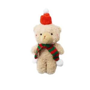 Adorable plush Christmas teddy bear wearing a red knit hat and a red-green striped scarf