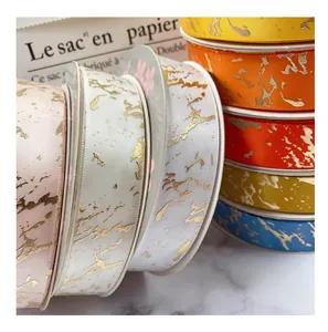 Detailed view of 2.5cm marble pattern ribbons in various colors with gold foil texture