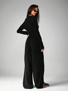 Back view of woman wearing elegant black long sleeve top and wide-leg trousers set