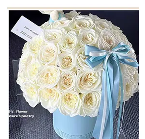 Detailed view of fresh white roses in a light blue floral hug bucket with blue ribbon