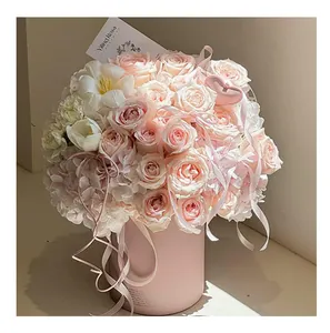 Close-up of pink matte round flower box with elegant rose bouquet and ribbons.
