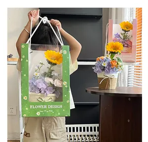 Nahaufnahme eines Kindes mit einer grünen Geschenktüte für Blumen mit Fenster und Sonnenblume
