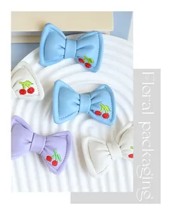 Dettaglio di fiocchi in pelle ricamati con ciliegie in vivaci colori pastello