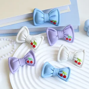 Accessori a fiocco in pelle imbottita con ricamo di ciliegie in colori pastello
