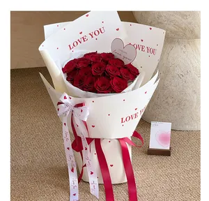 Close-up detail of white floral wrapping paper with red hearts and LOVE YOU printed text