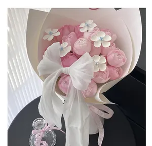 Close-up of a large white pearlescent chiffon bow decorating a bouquet of pink roses