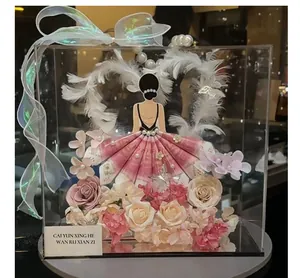 Detalle de una elegante caja de regalo de acrílico con un vestido de billetes rosa y corazón