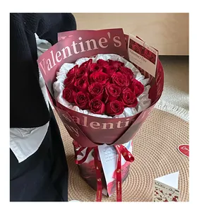 Elegant hand-held bouquet of red roses wrapped in dark red waterproof Valentine's paper.