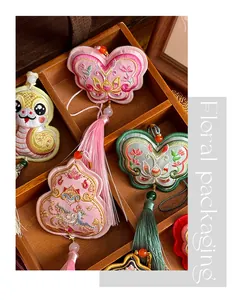 Detail showing variety of traditional Chinese embroidered sachet pendants in wooden box