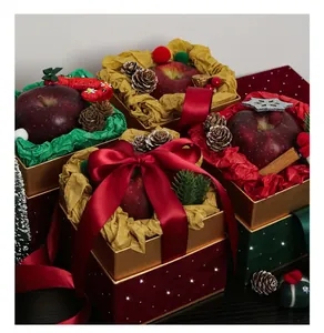 Primo piano di lussuose scatole regalo in velluto con mele rosse e nastri festivi